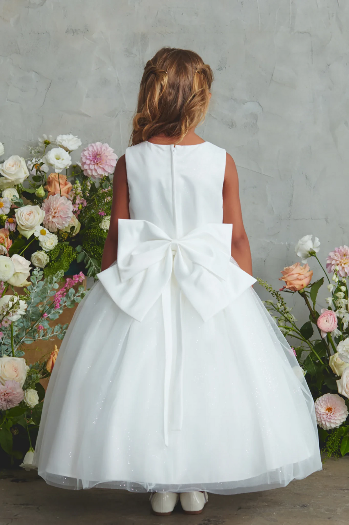 Dramatic satin loops form a pointed bow on the off-white flower girl dress.