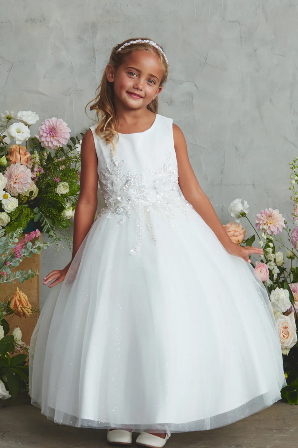 Flower appliques spread across the off-white flower girl dress's waist.