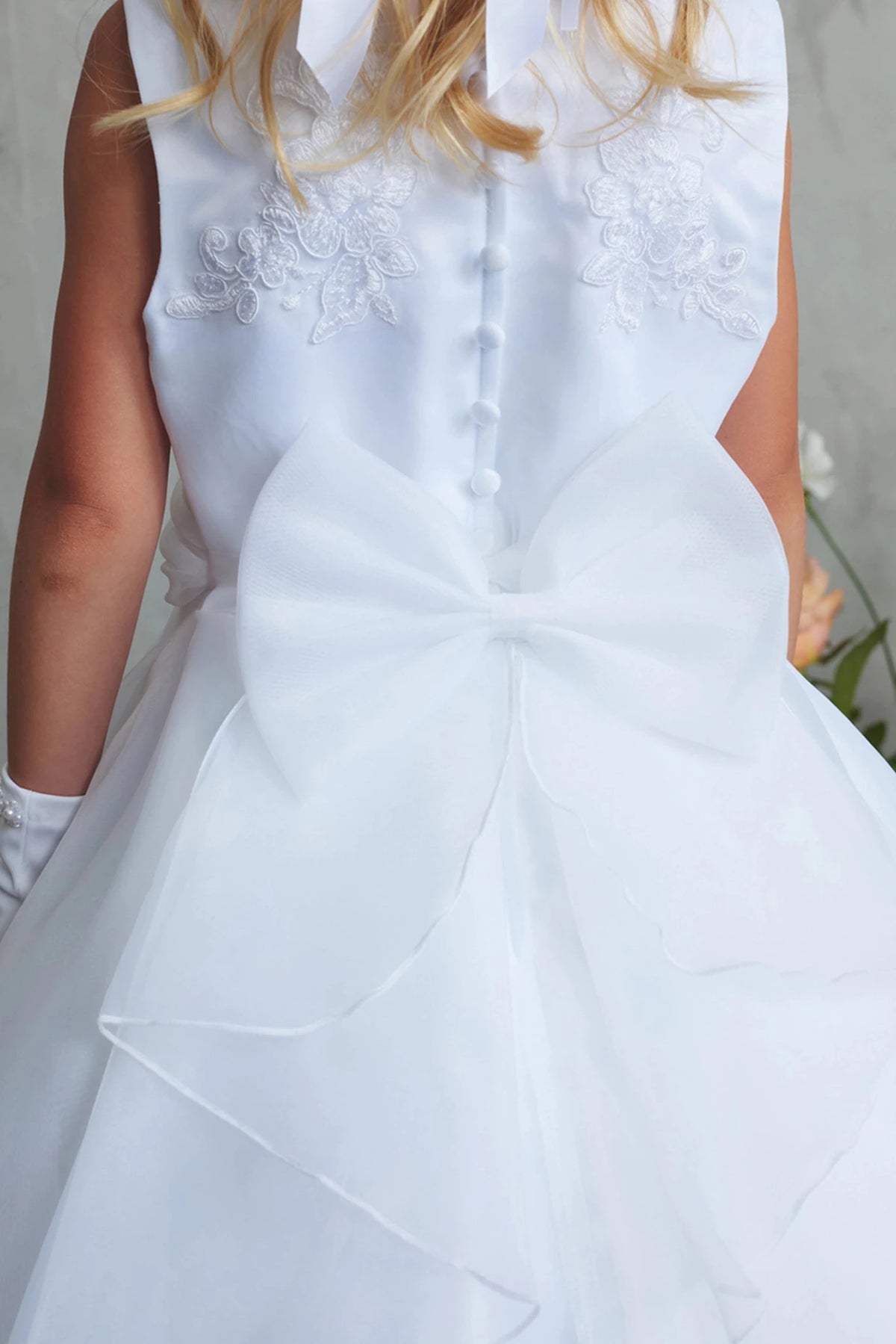 Highlighting buttoned embroidered back on a white flower girl dress.
