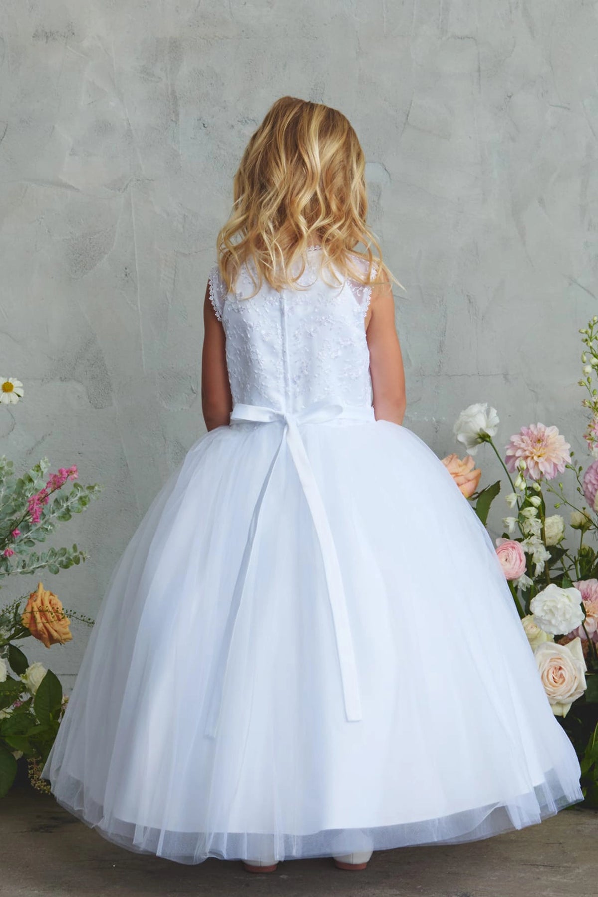 White flower girl dress detailed with a slender satin sash.