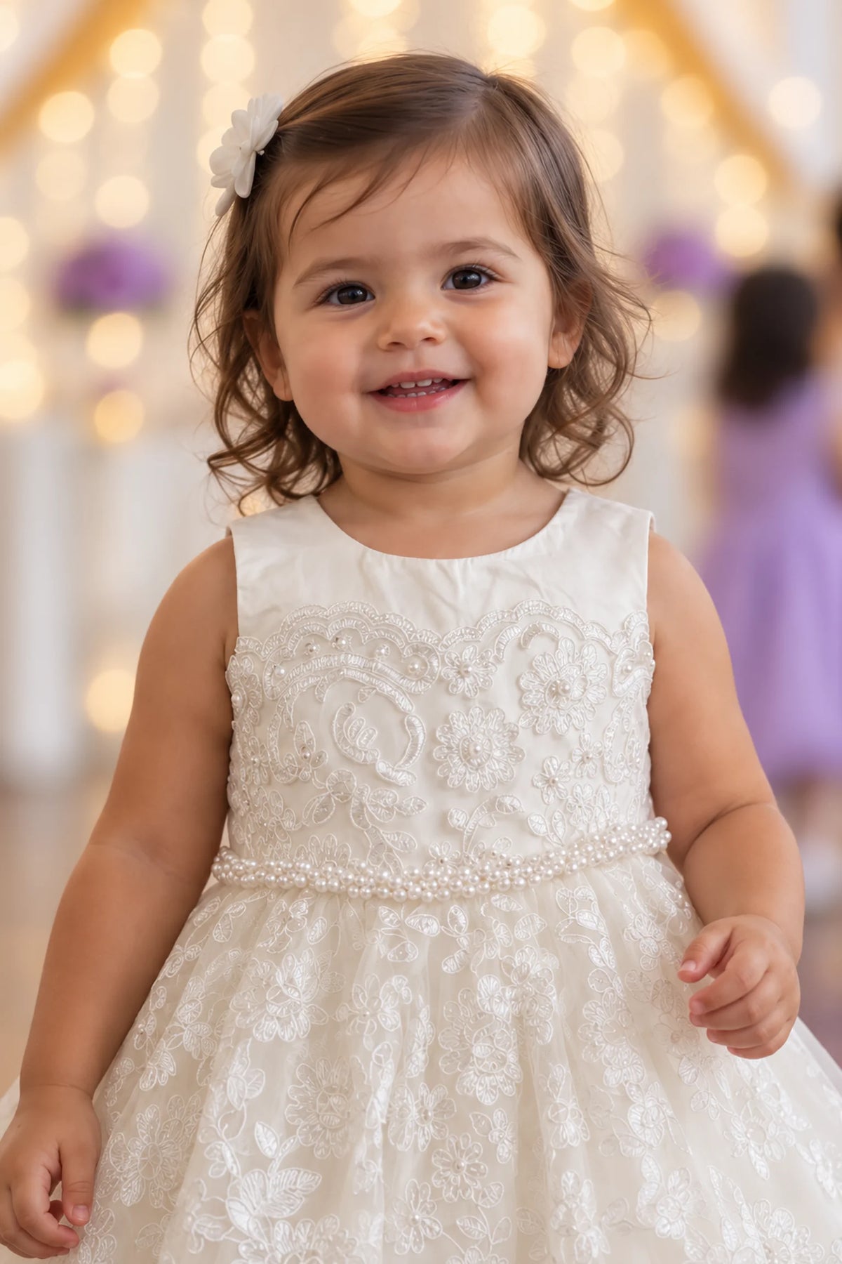 Floral lace covers the bodice of this ivory flower girl dress above its pearl waist.
