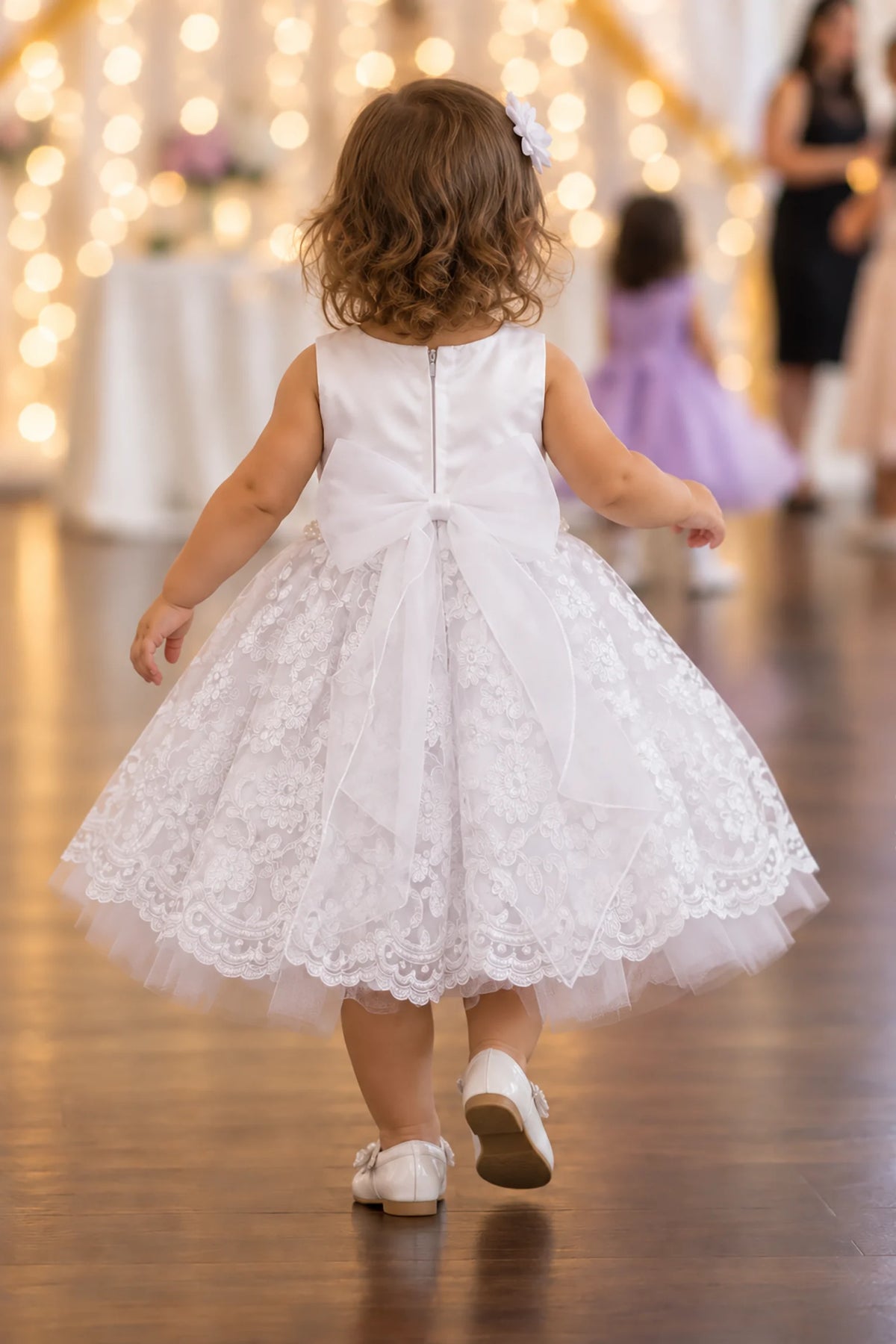 Rear zipper and large bow finish the white flower girl dress.