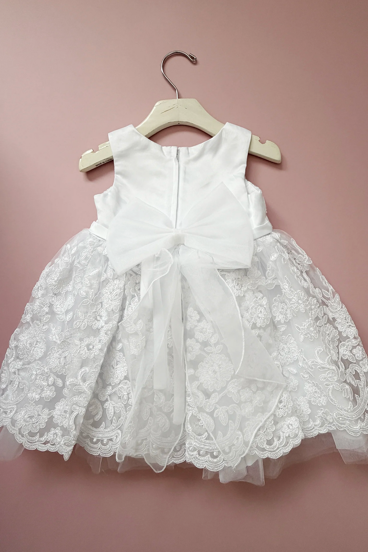 Sheer bow tails extend over the white flower girl dress skirt.