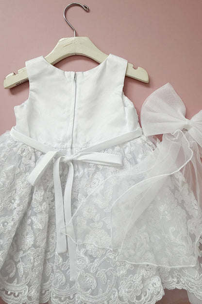 Close-up of the white flower girl dress shows its zipper and tied bow.