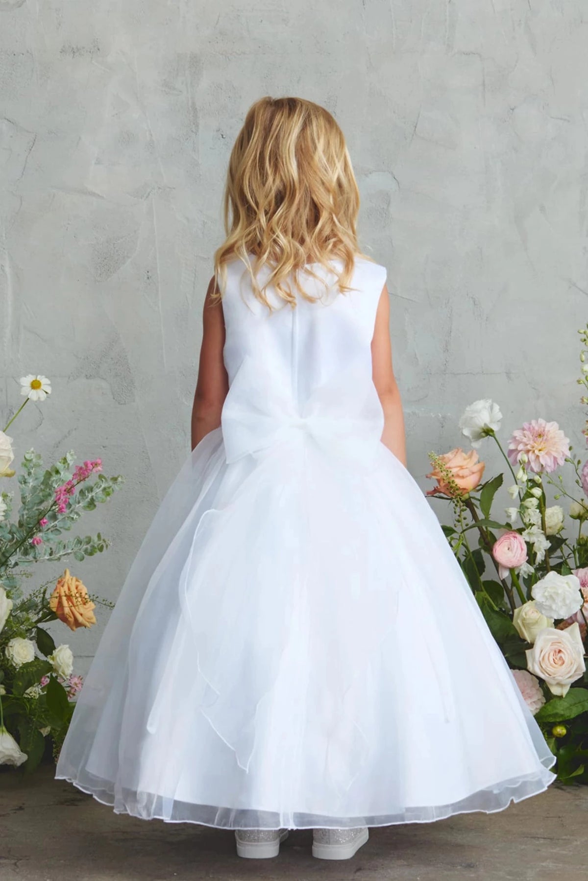 White flower girl dress featuring a small tied back bow.