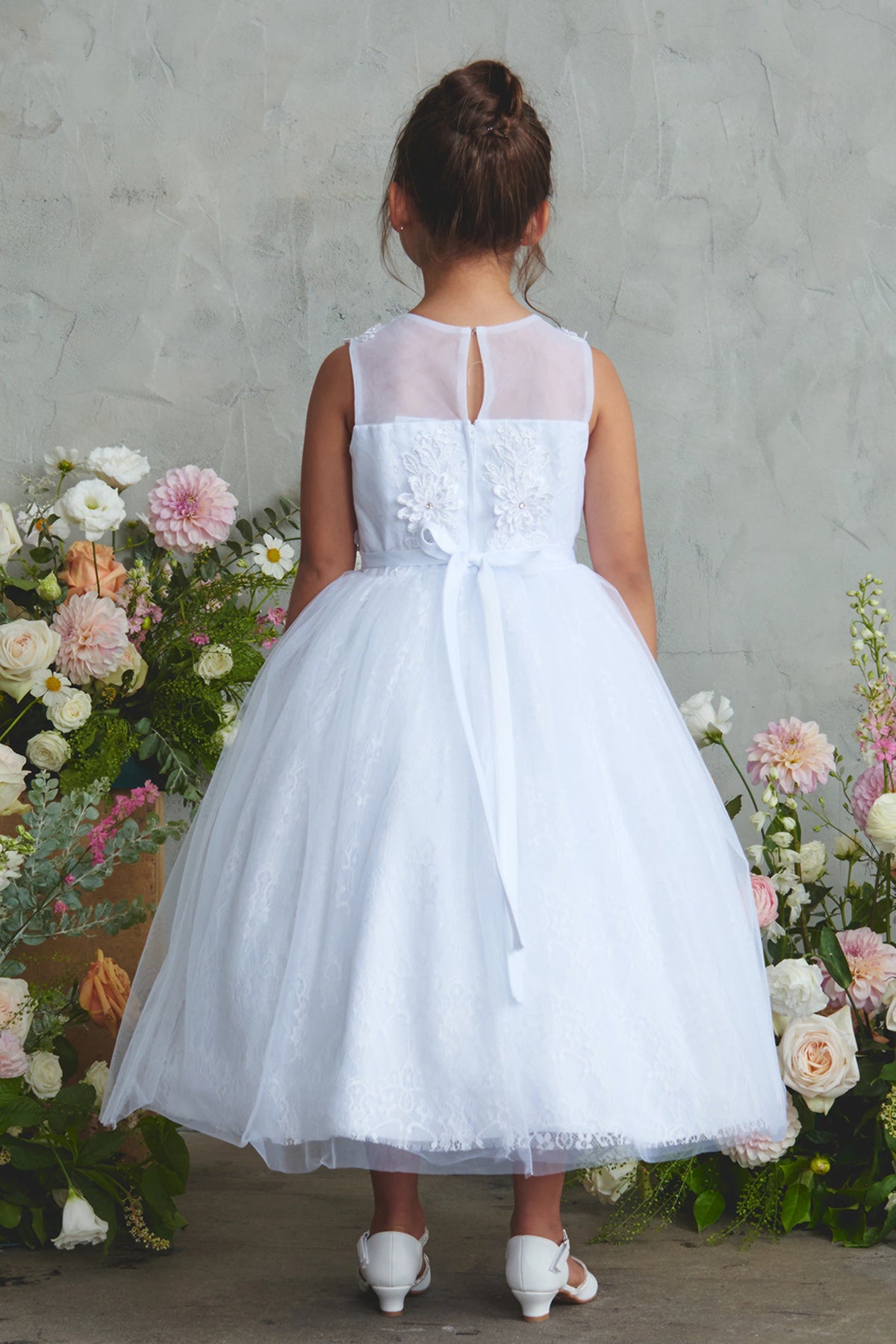 Large satin back bow on a white flower girl dress.