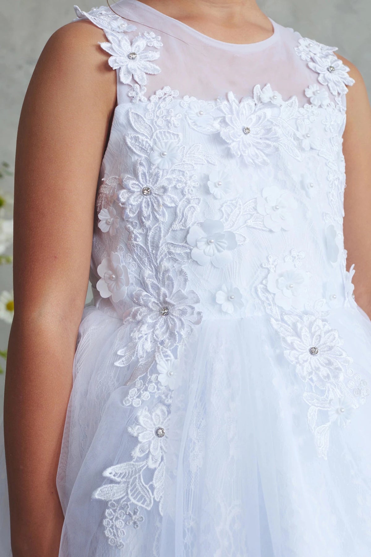 In view: dimensional lace blossoms of a white flower girl dress.