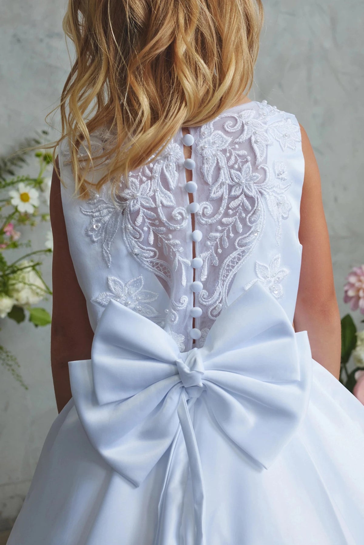 Oversized satin bow accents this white flower girl dress.