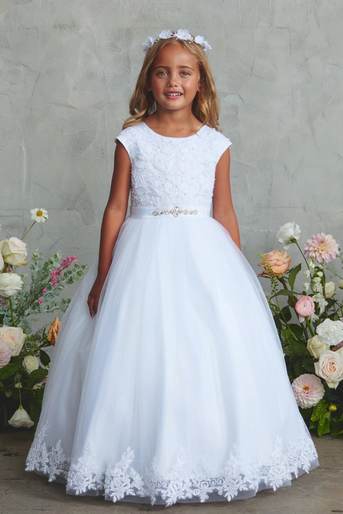 White flower girl dress detailed with a floral lace hem.