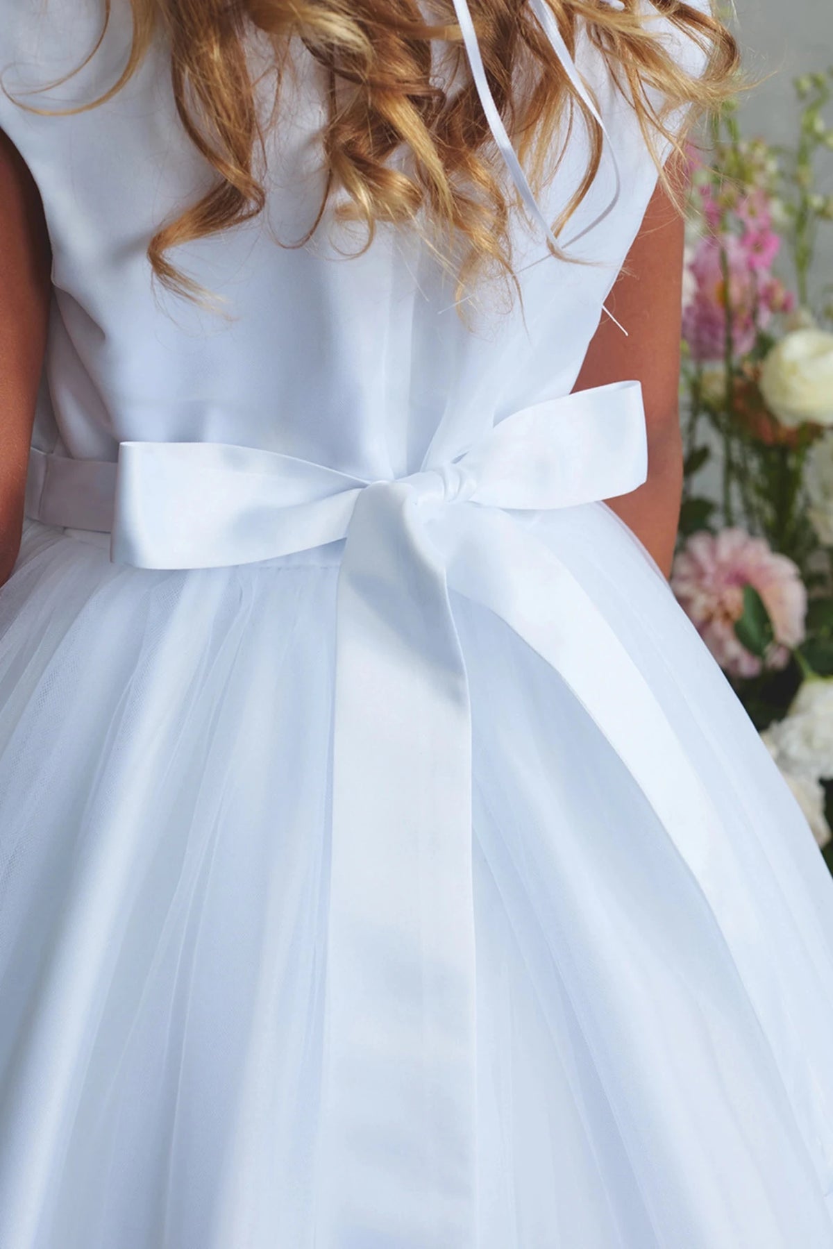 This white flower girl dress displays a small satin waist bow.