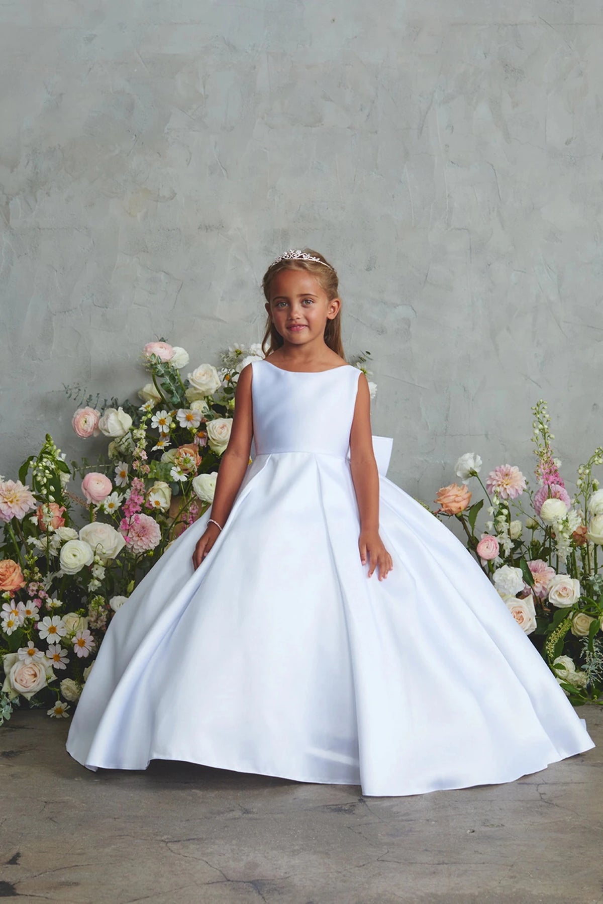 Featuring a wide satin hem, a white flower girl dress.