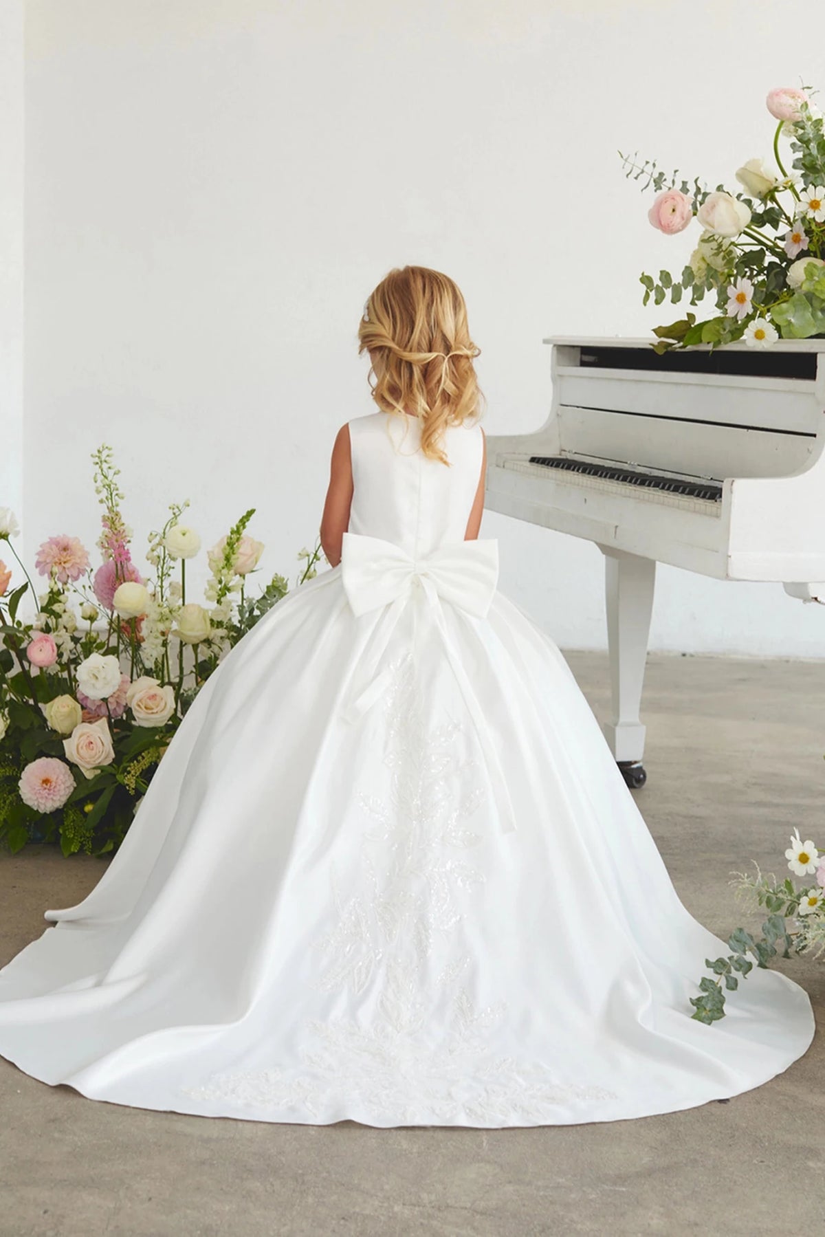 Focus on a long lace-trimmed train of the white flower girl dress.