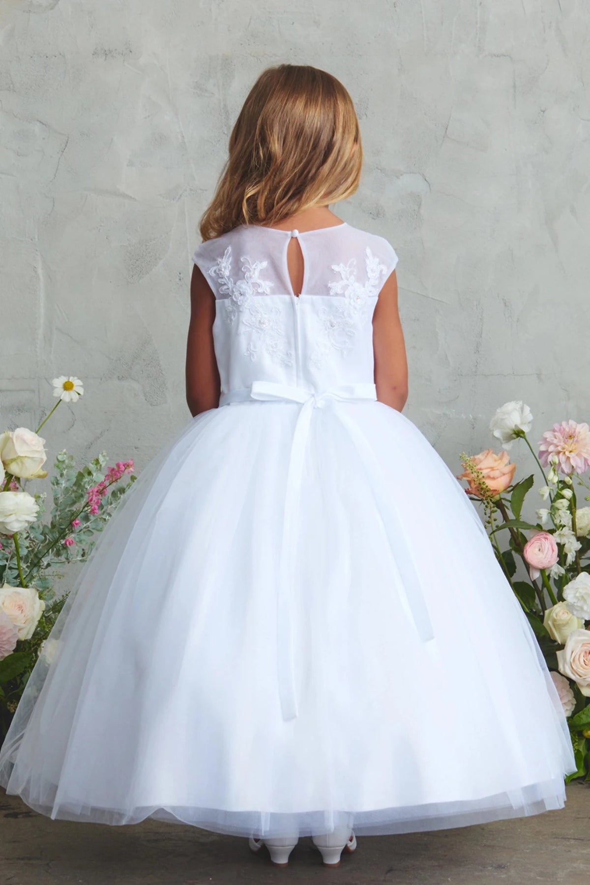 Emphasis on sheer floral back of the white flower girl dress.