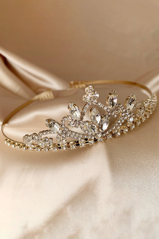 Gold tiara with dainty crystals on a beige satin background