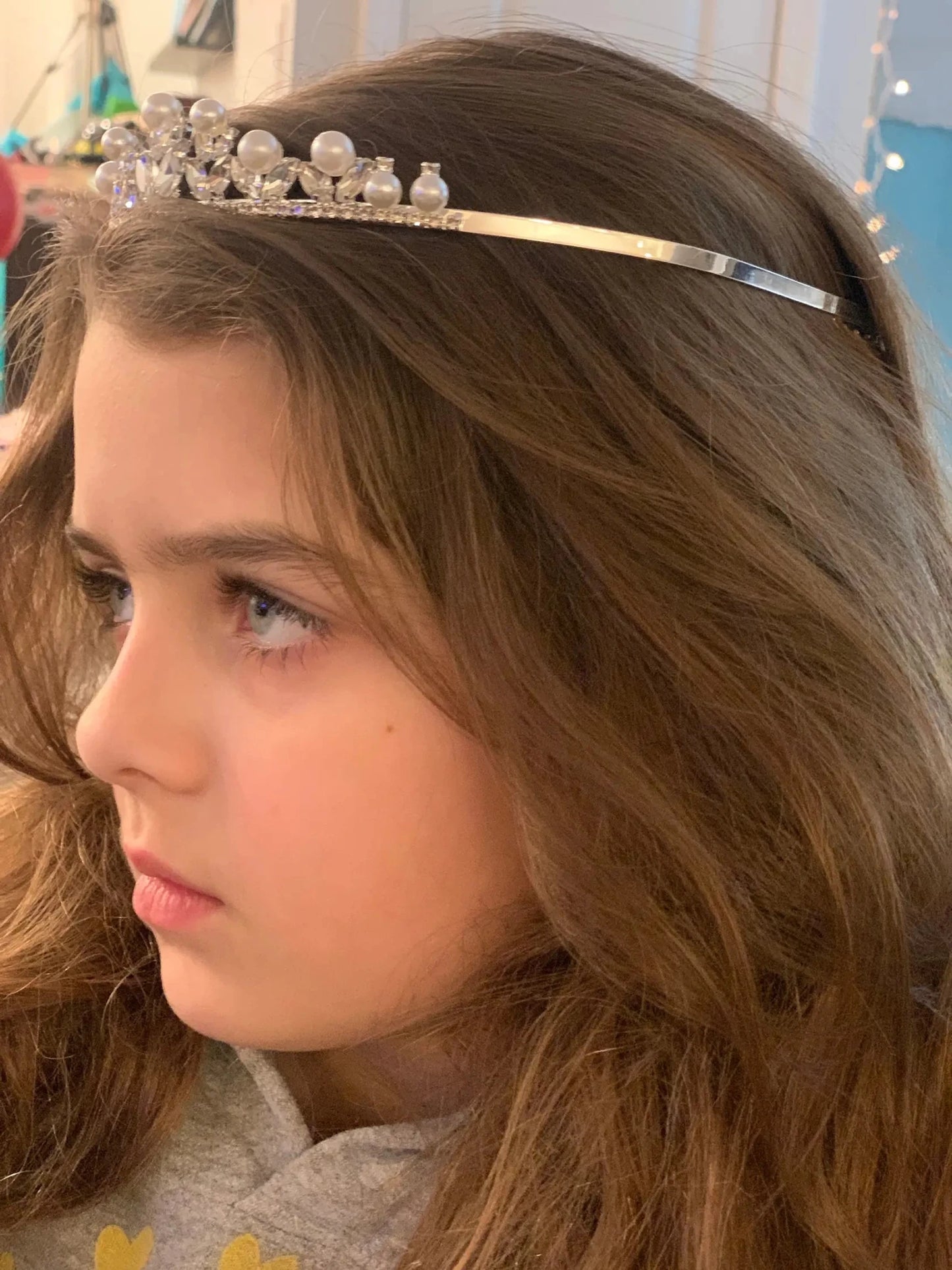 Young girl wearing a decorative tiara with big pearls and rhinestones