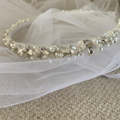 Pearl and crystal headband with tulle veil on a neutral background