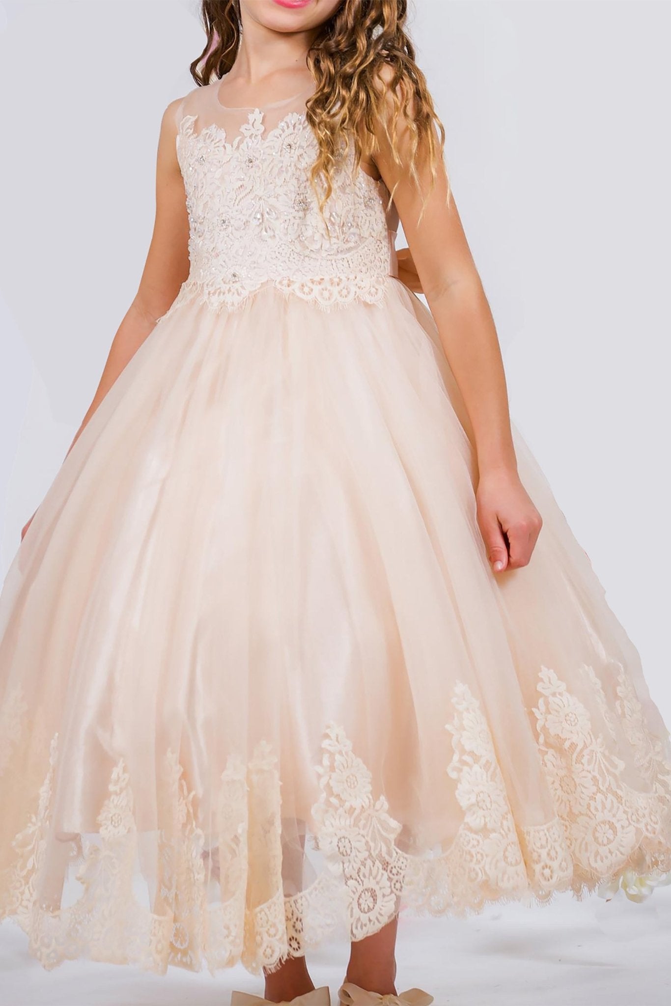 A beige lace tulle communion dress. top of the dress is see though with rhinestones and pearls.