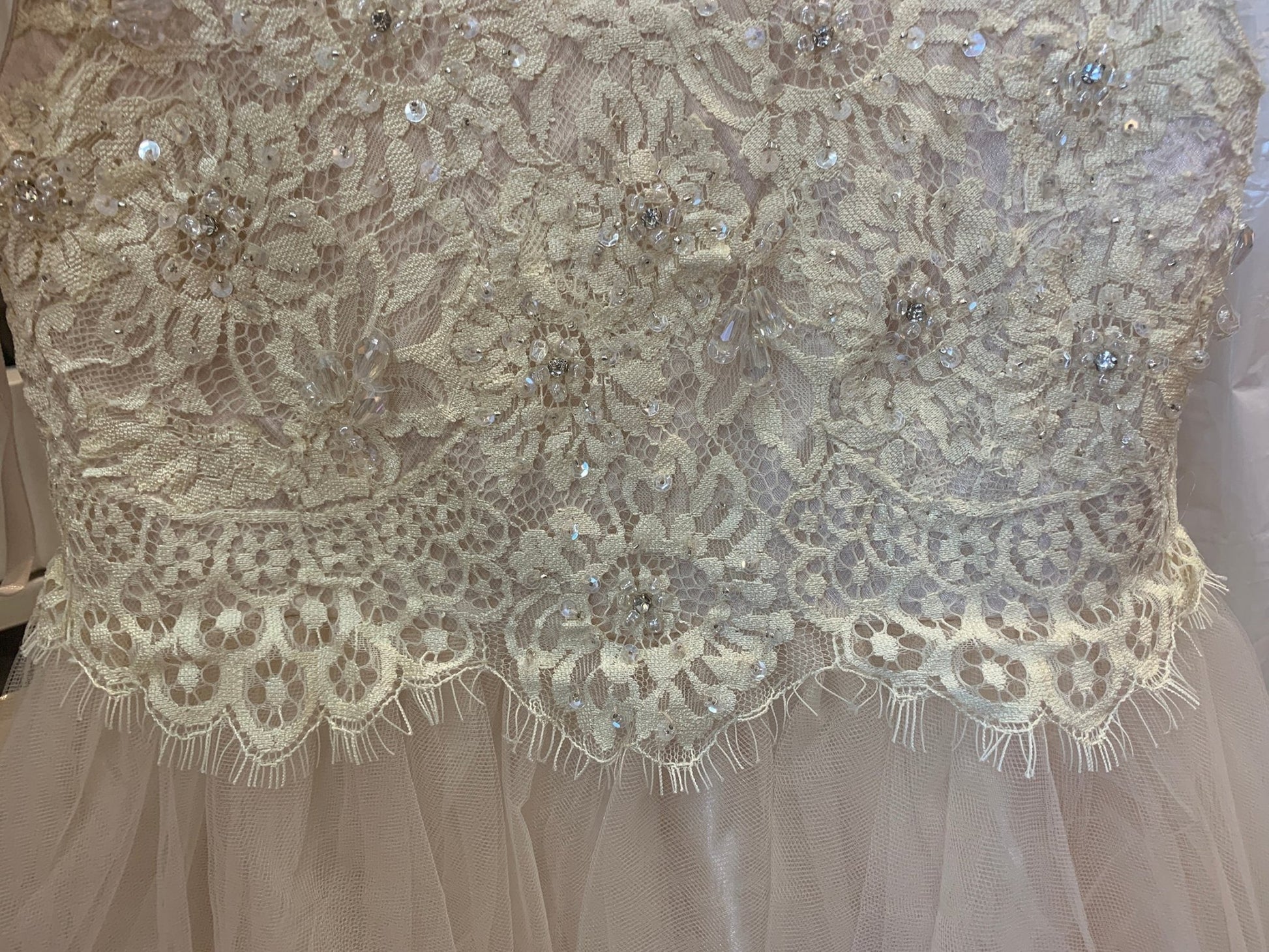 Close-up of a lace communion dress with intricate patterns and embellishments.