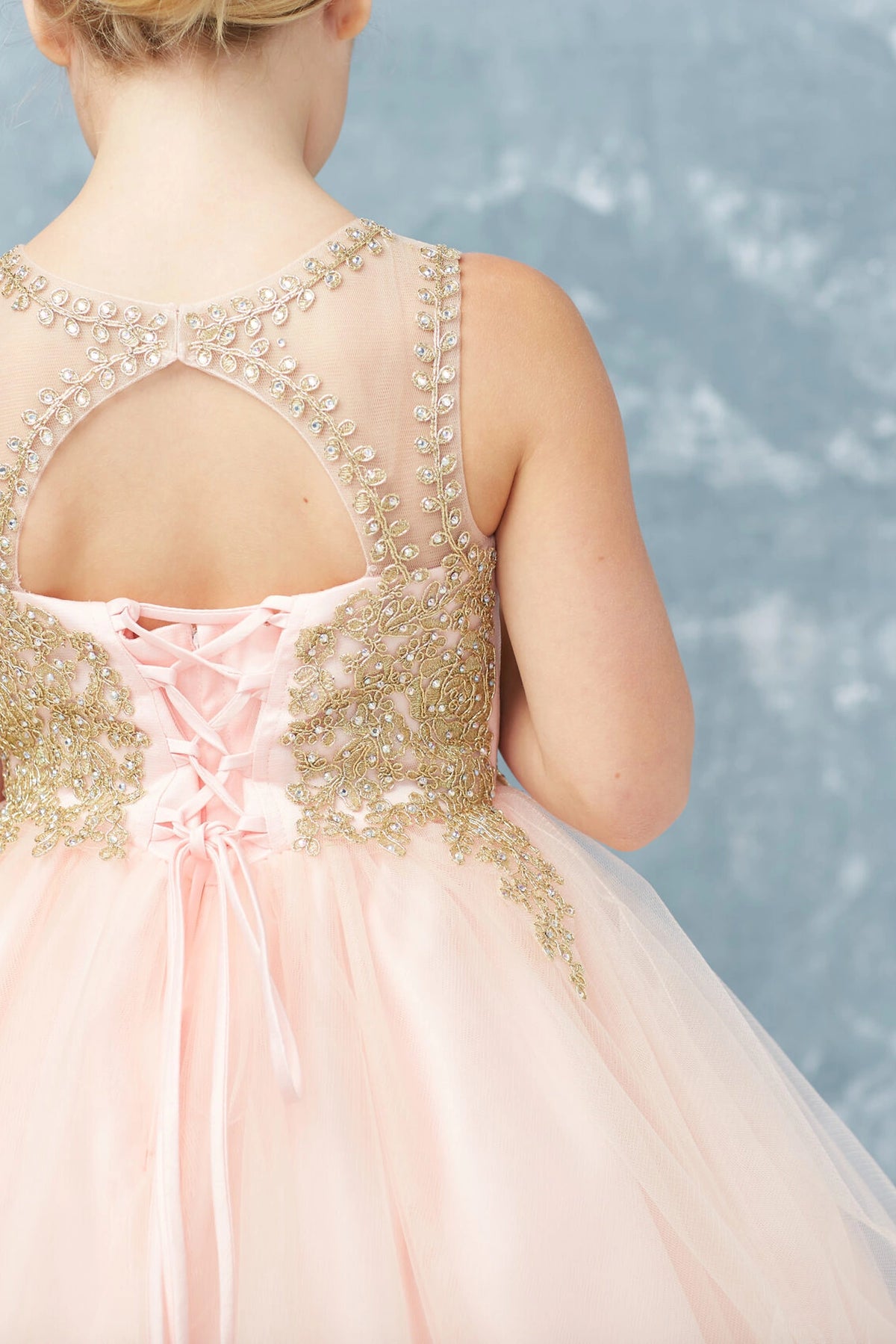 Seen from up close, this Blush kids pageant dress displays metallic lace edging at the keyhole back.