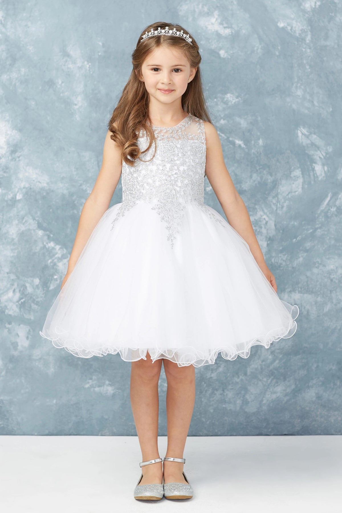The White kids pageant dress has metallic floral lace.