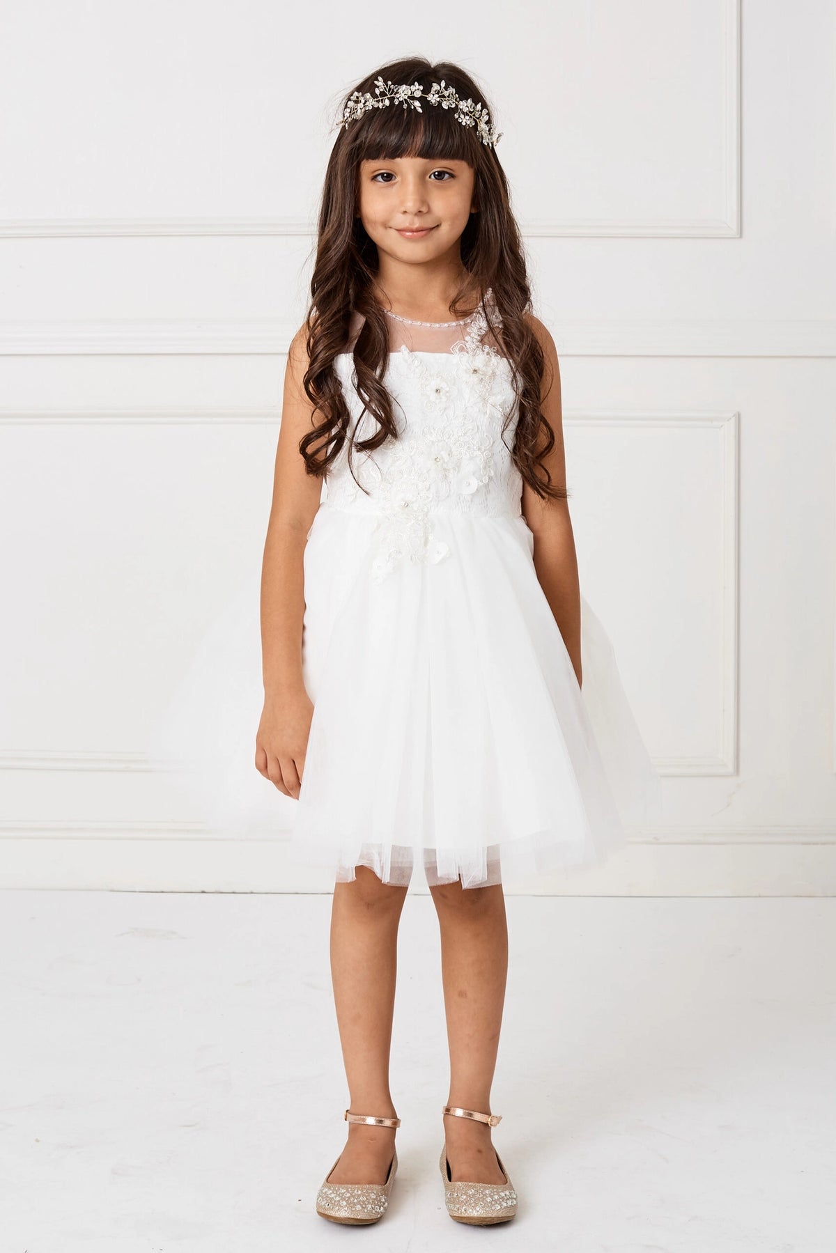 The white flower girl dress features an asymmetric floral applique.