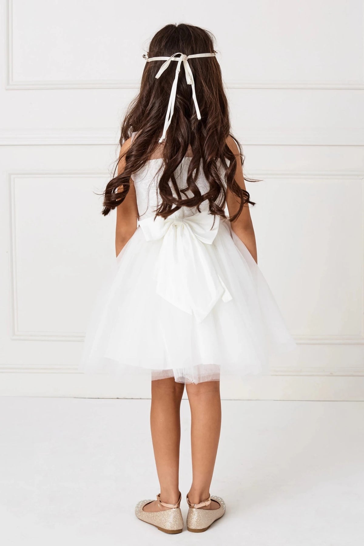 With a flowing back ribbon, a white flower girl dress.