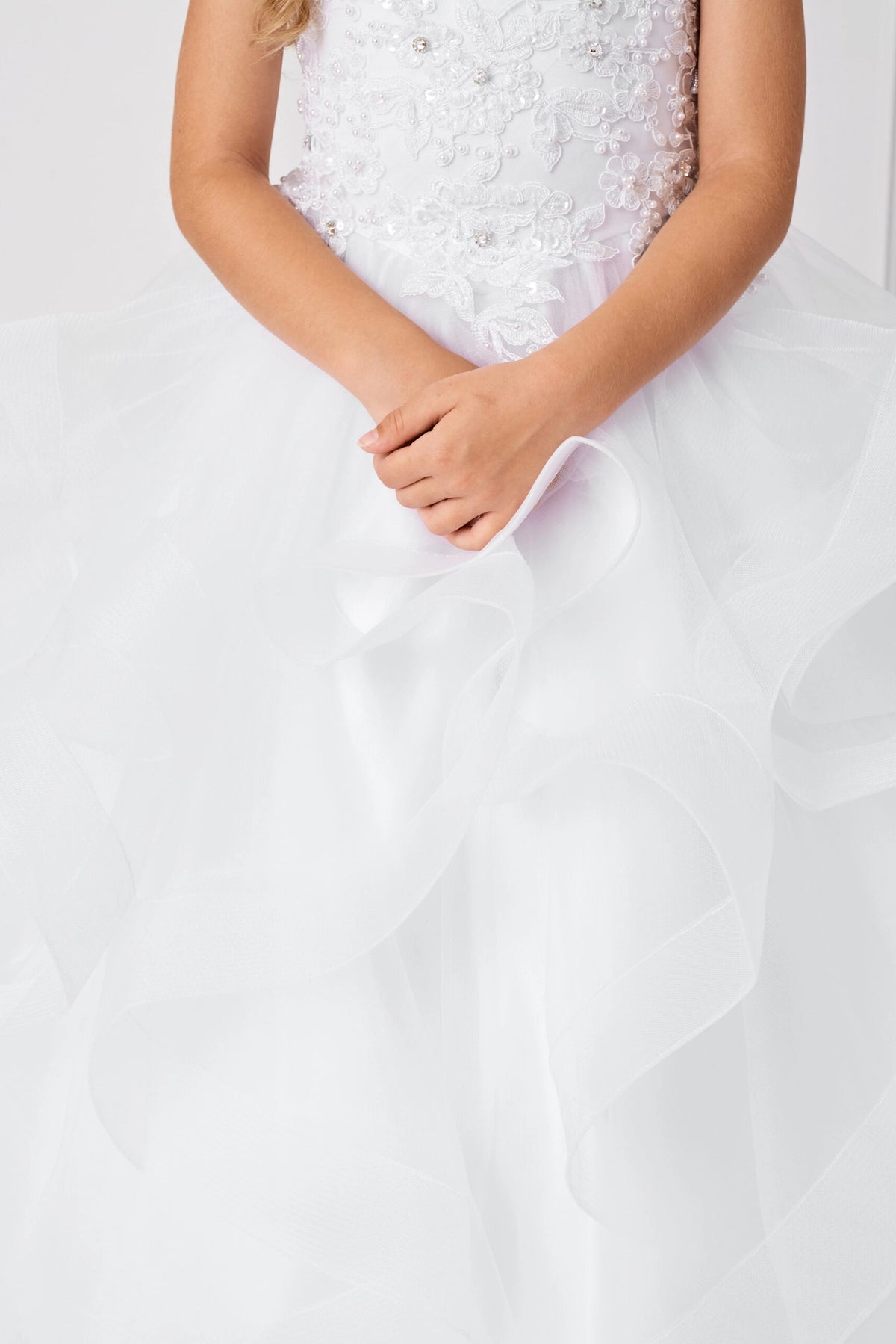 Seen from up close, this White kids pageant dress displays beaded lace at the waist.