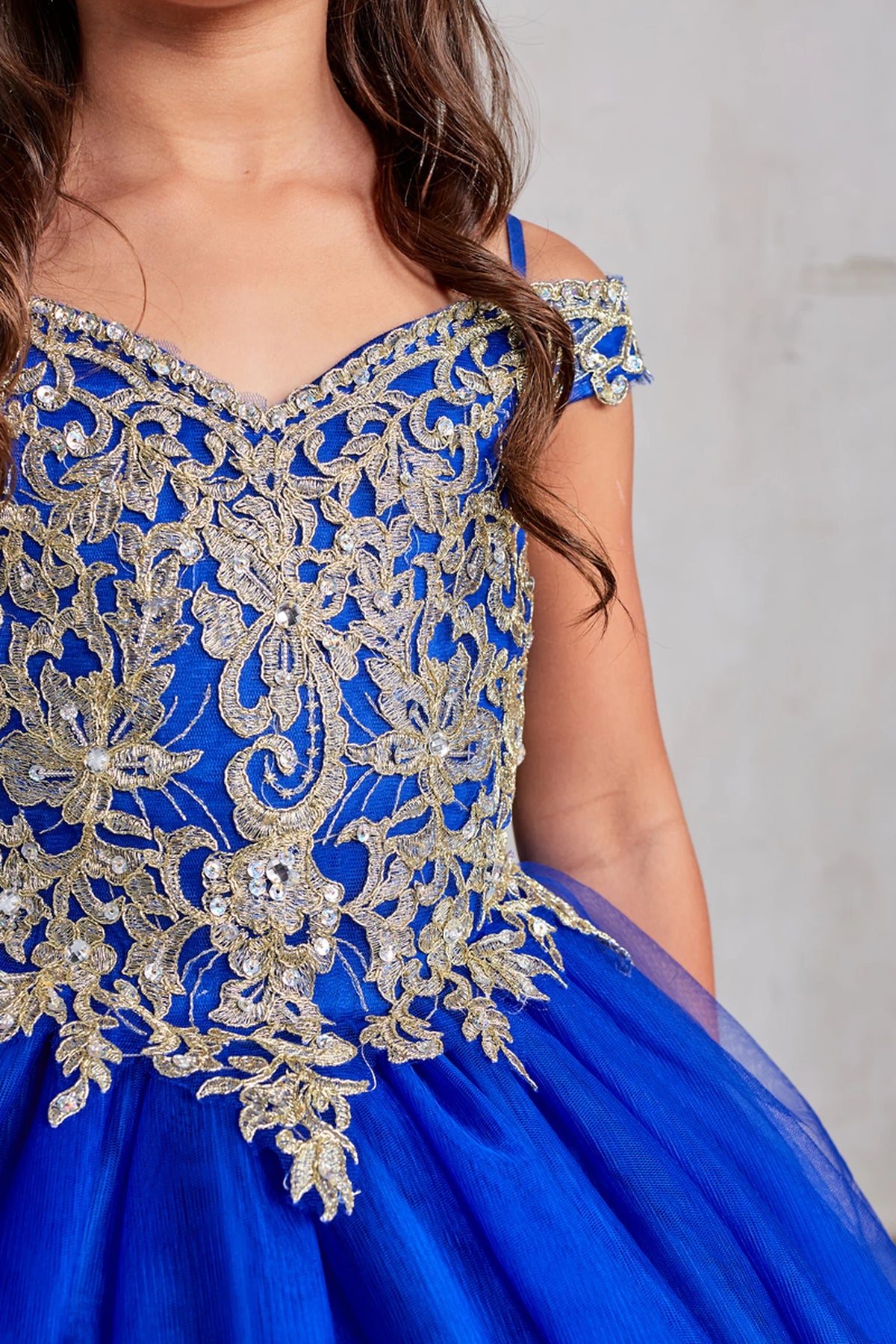 On the Royal Blue kids pageant dress, the detailing includes gold floral embroidery across the bodice.