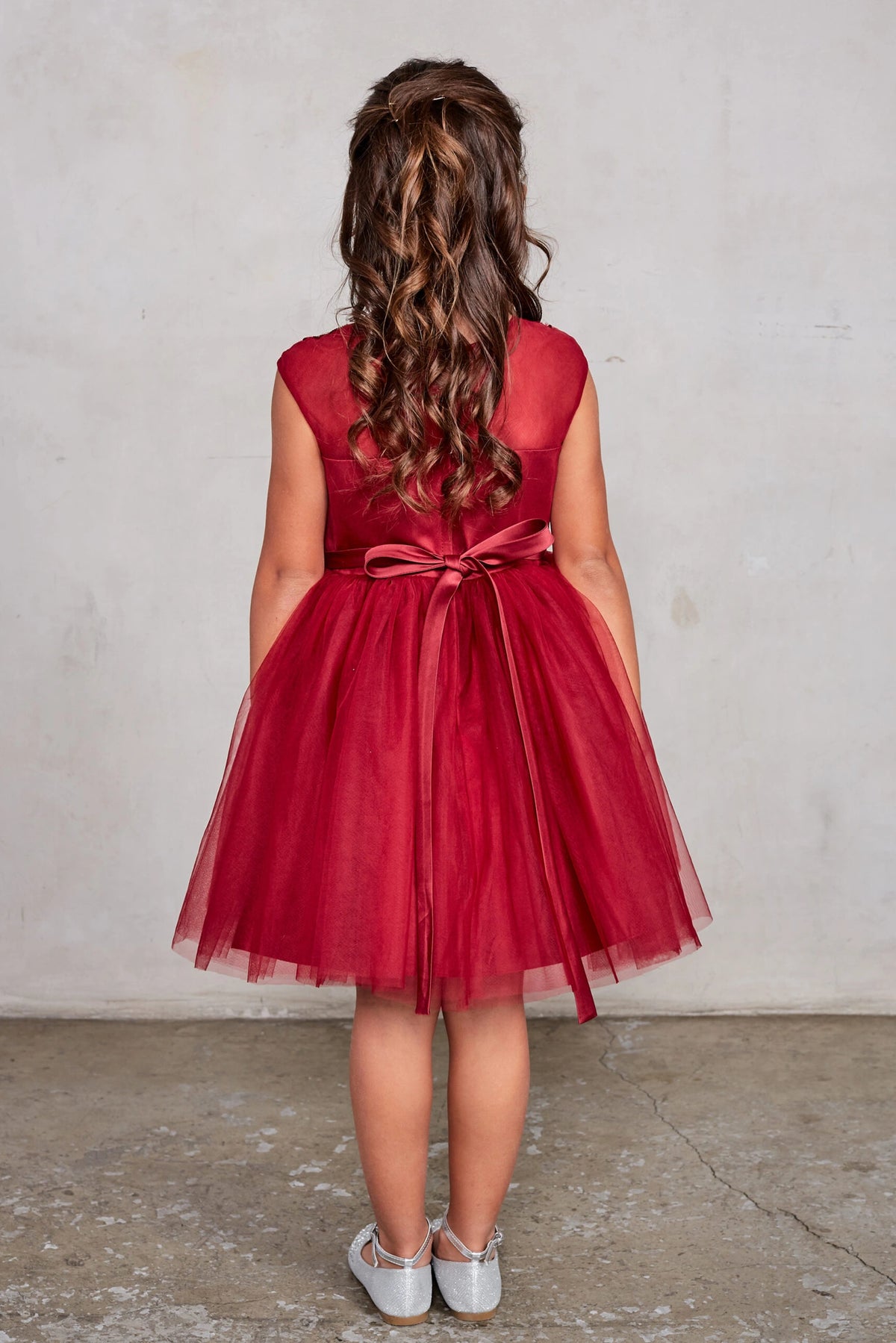 Seen from behind, this Burgundy kids pageant dress displays a tied sash across the back waist.