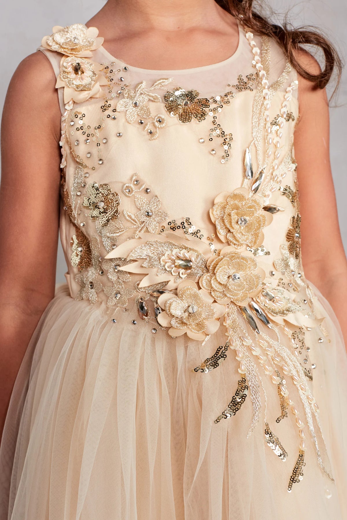 The Gold kids pageant dress has dimensional flowers along the illusion neckline.