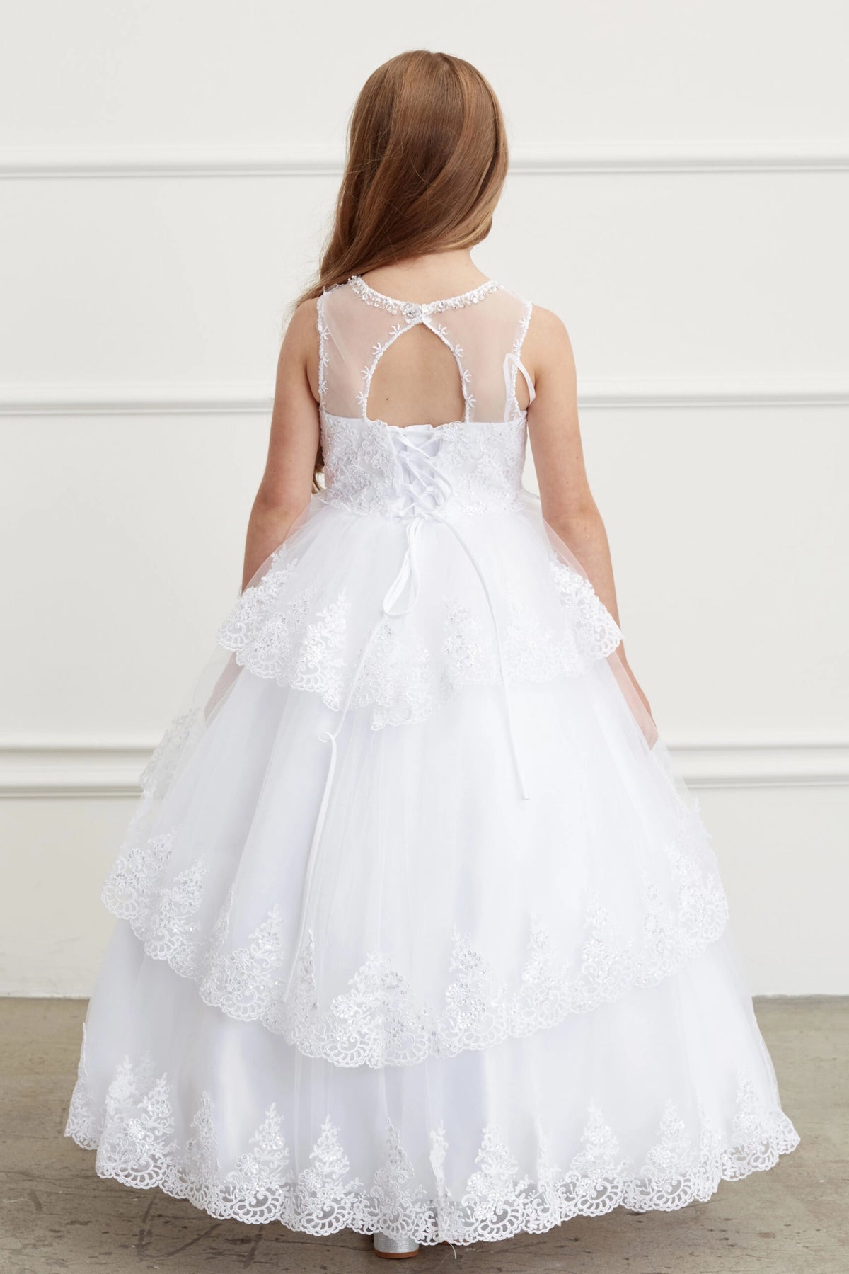 White kids pageant dress featuring lace-up ties at the back.