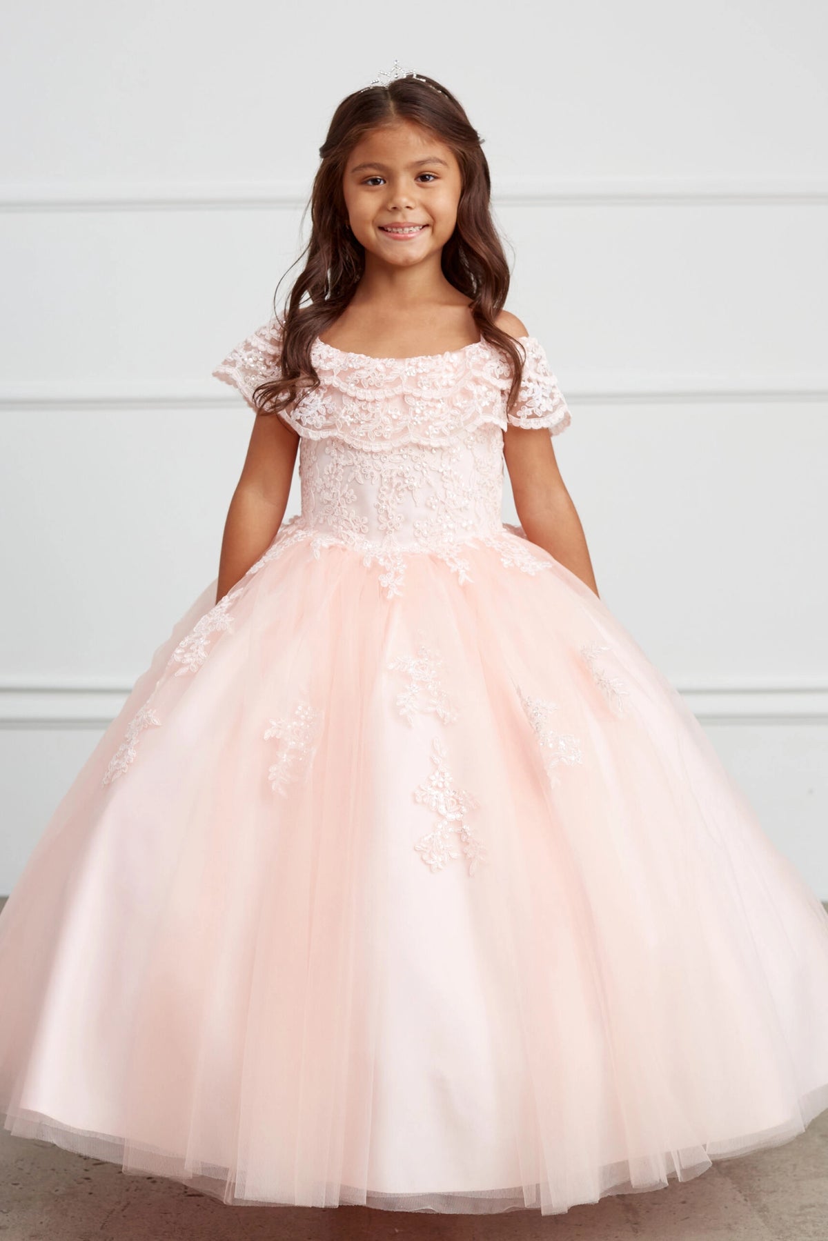 Blush kids pageant dress featuring a ruffled off-the-shoulder neckline.
