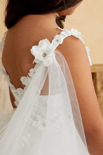 Seen from up close, this Ivory kids pageant dress displays floral trim at the shoulder.