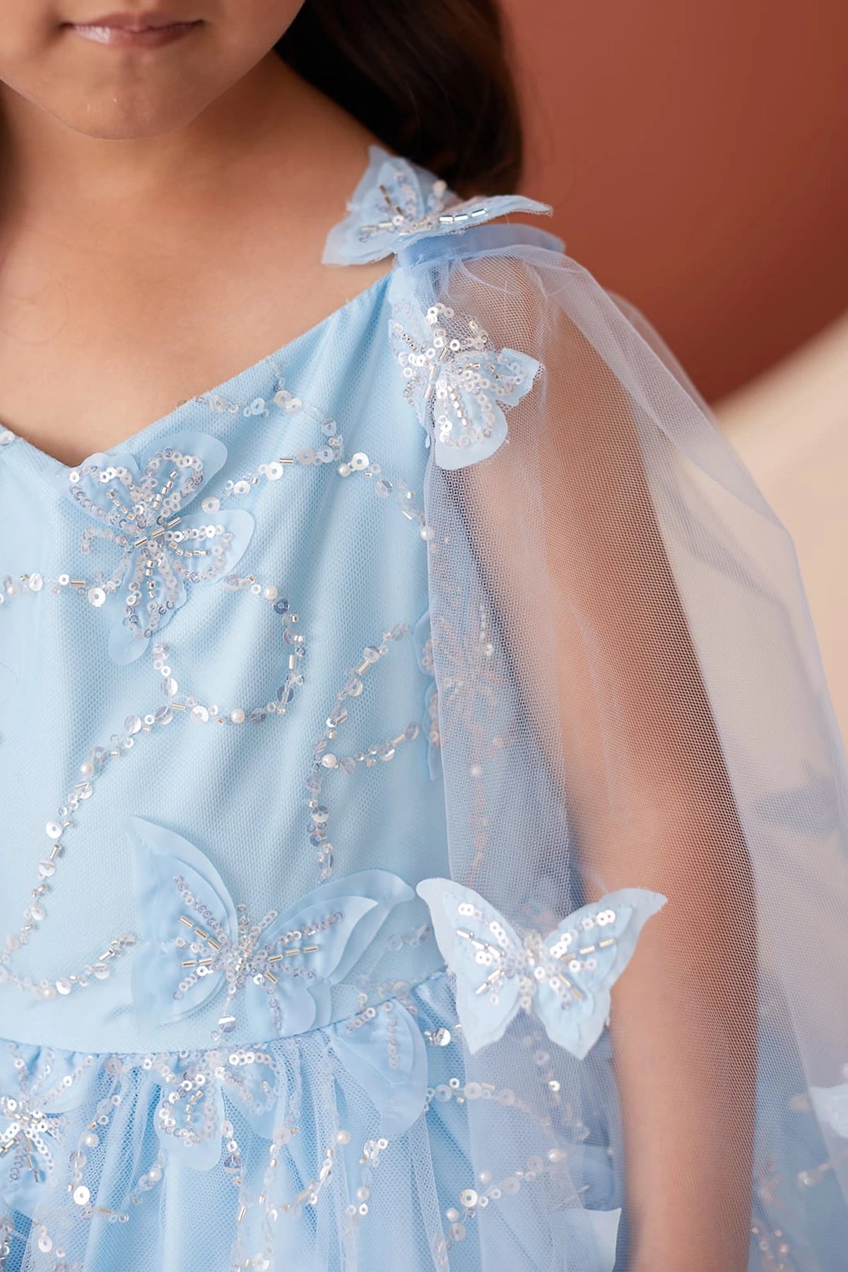 Visible details on the Sky Blue kids pageant dress include butterflies on a sheer cape.