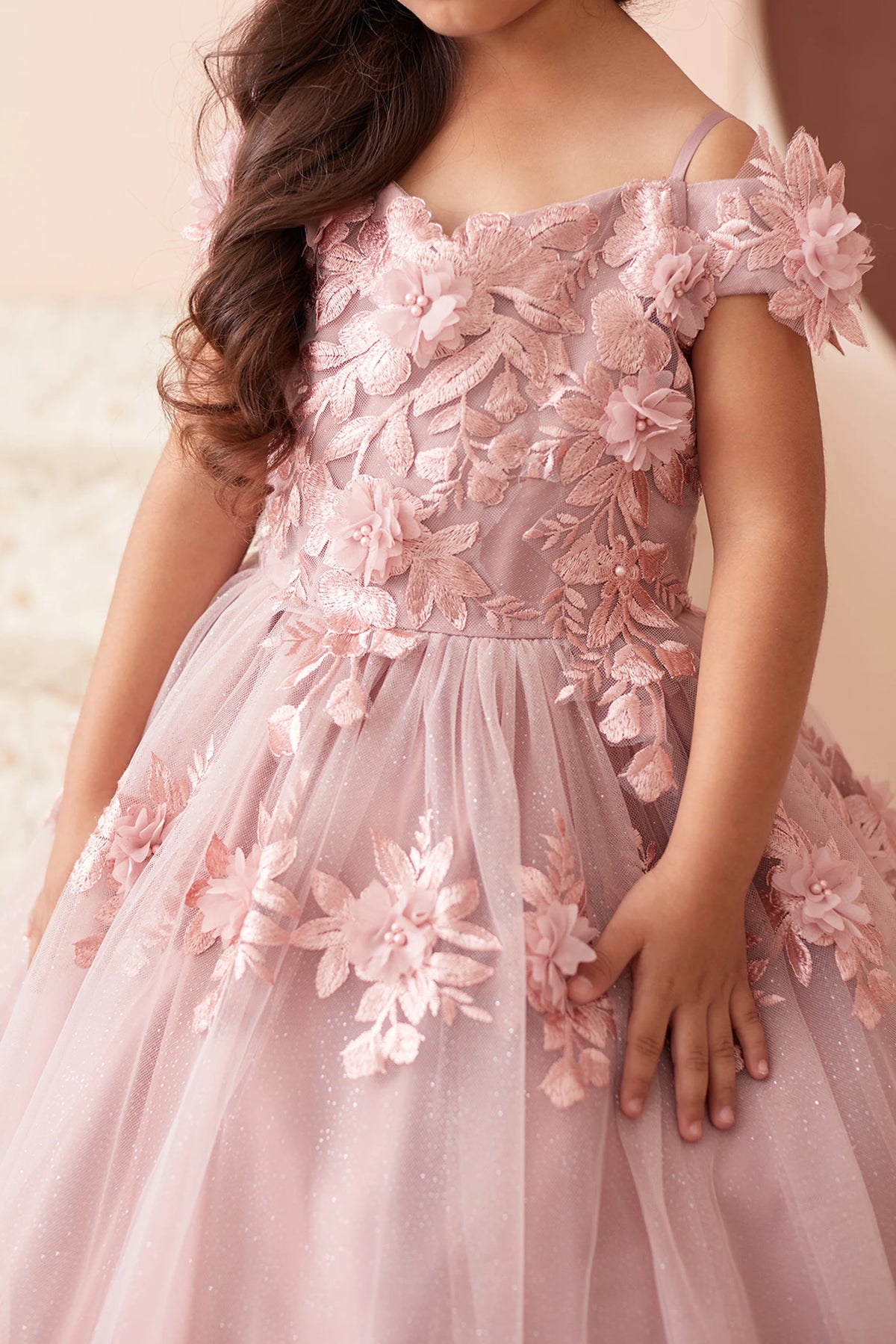 The Dusty Rose kids pageant dress has dimensional lace flowers across the bodice.