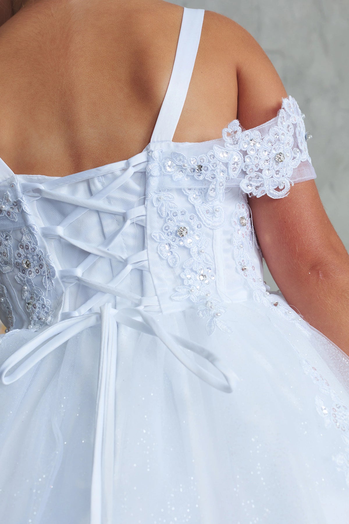The White kids pageant dress has lacing beneath the shoulder straps.