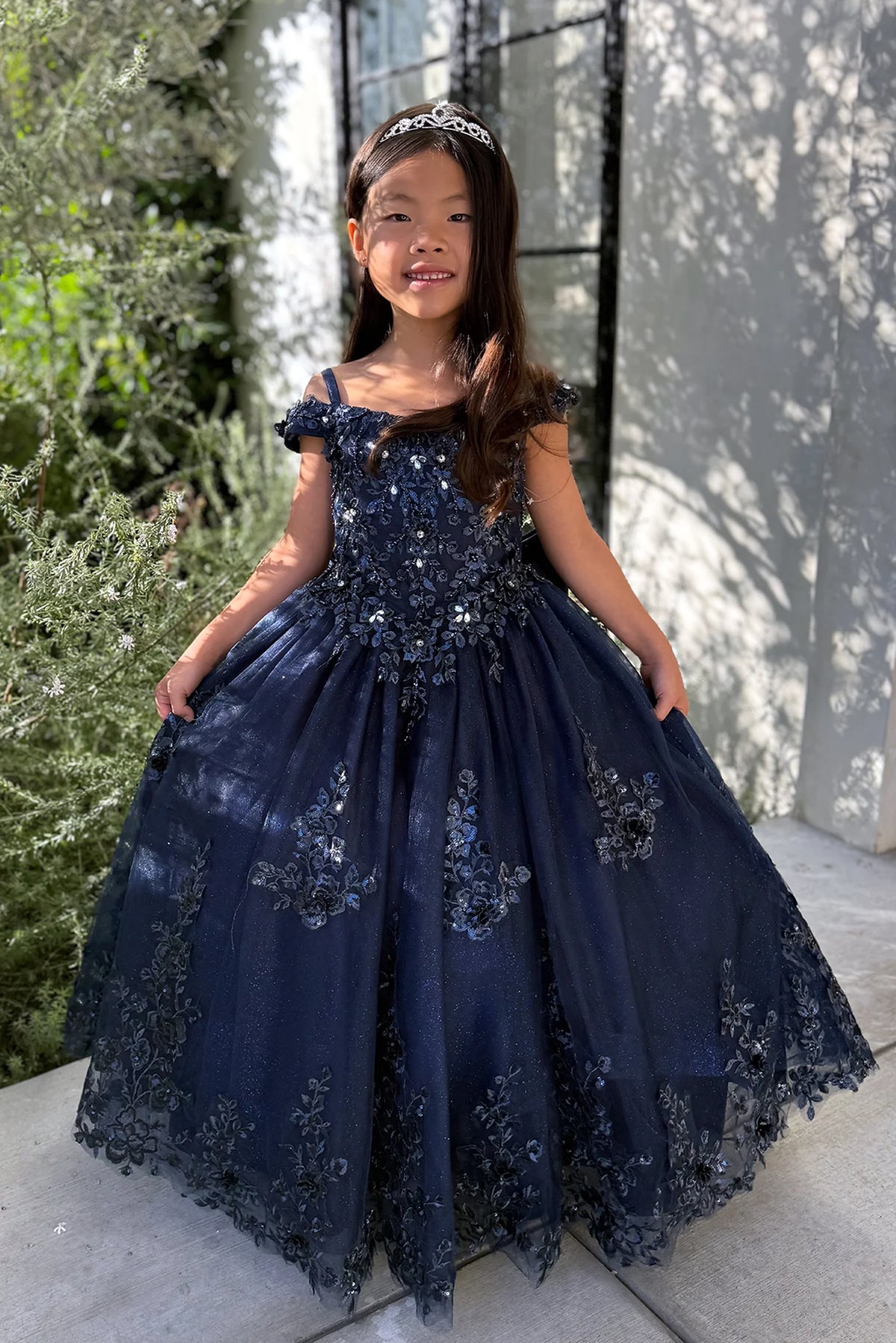 The Navy Blue kids pageant dress has lace appliques on a glitter tulle skirt.
