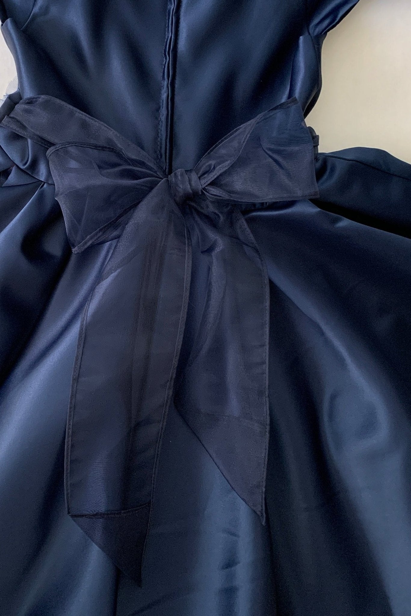Navy blue flower girl dress with a large bow detail.