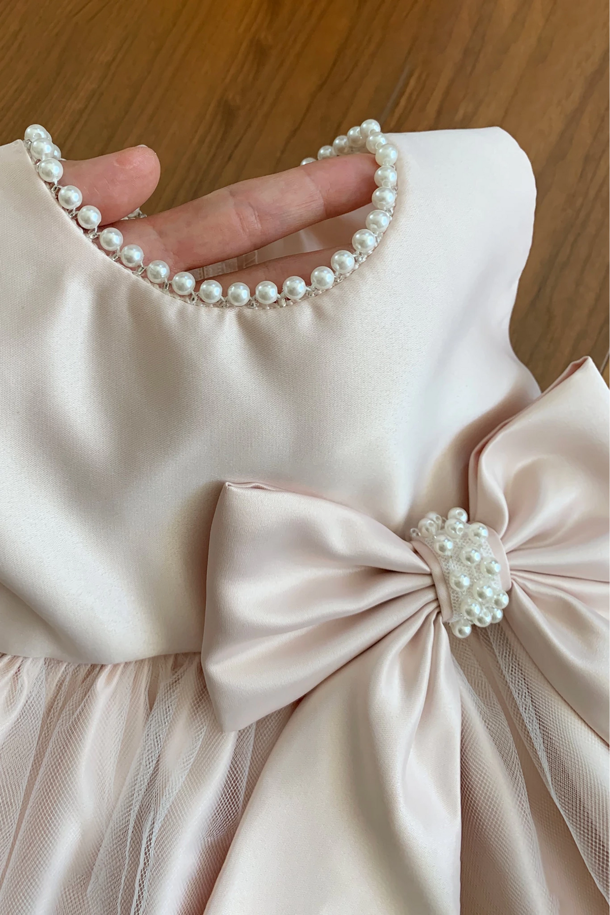Pink flower girl dress with a large bow and pearl embellishments around the neck part.