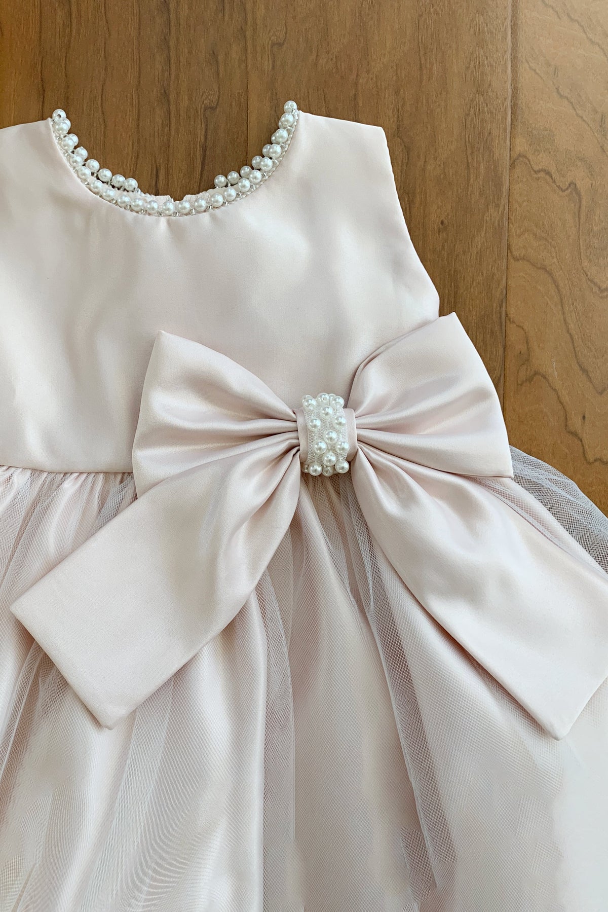 White flower girl dress with a large bow and pearl embellishments.