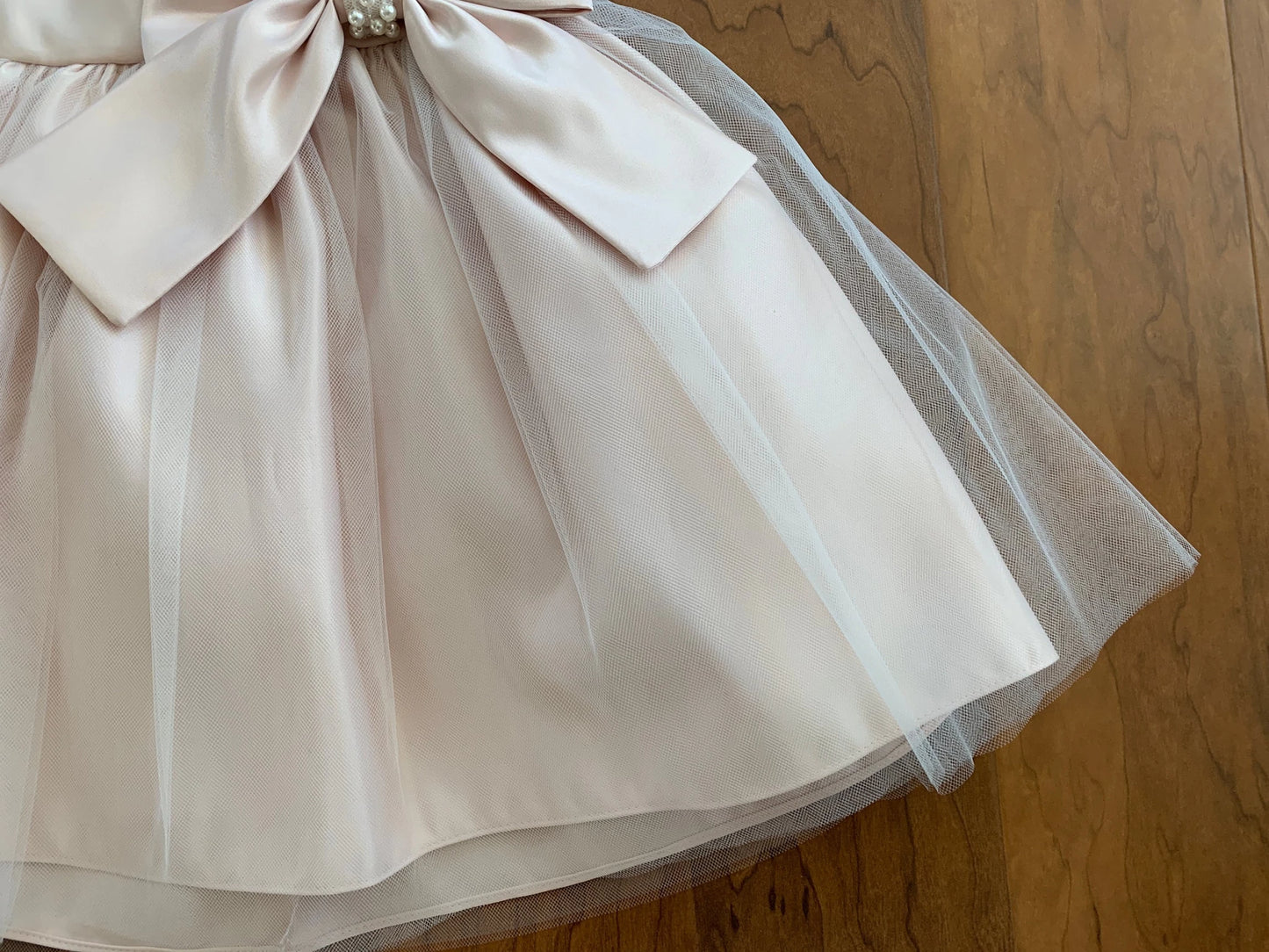 Blush tulle flower girl dress with a large bow.