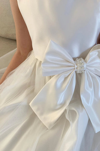 Textured details appear across ivory flower girl dress with a large bow detail.