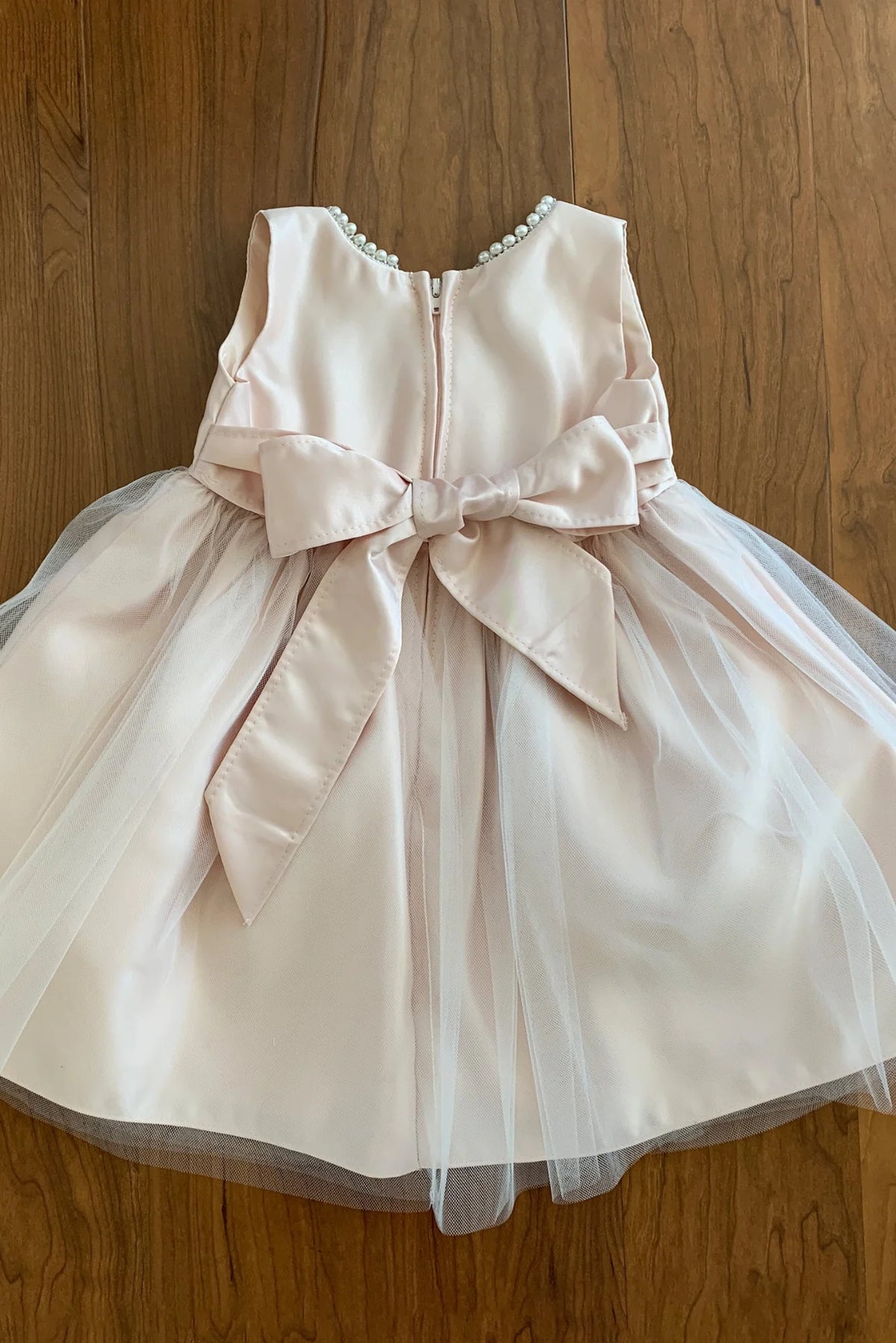 Blush flower girl dress with a large bow.