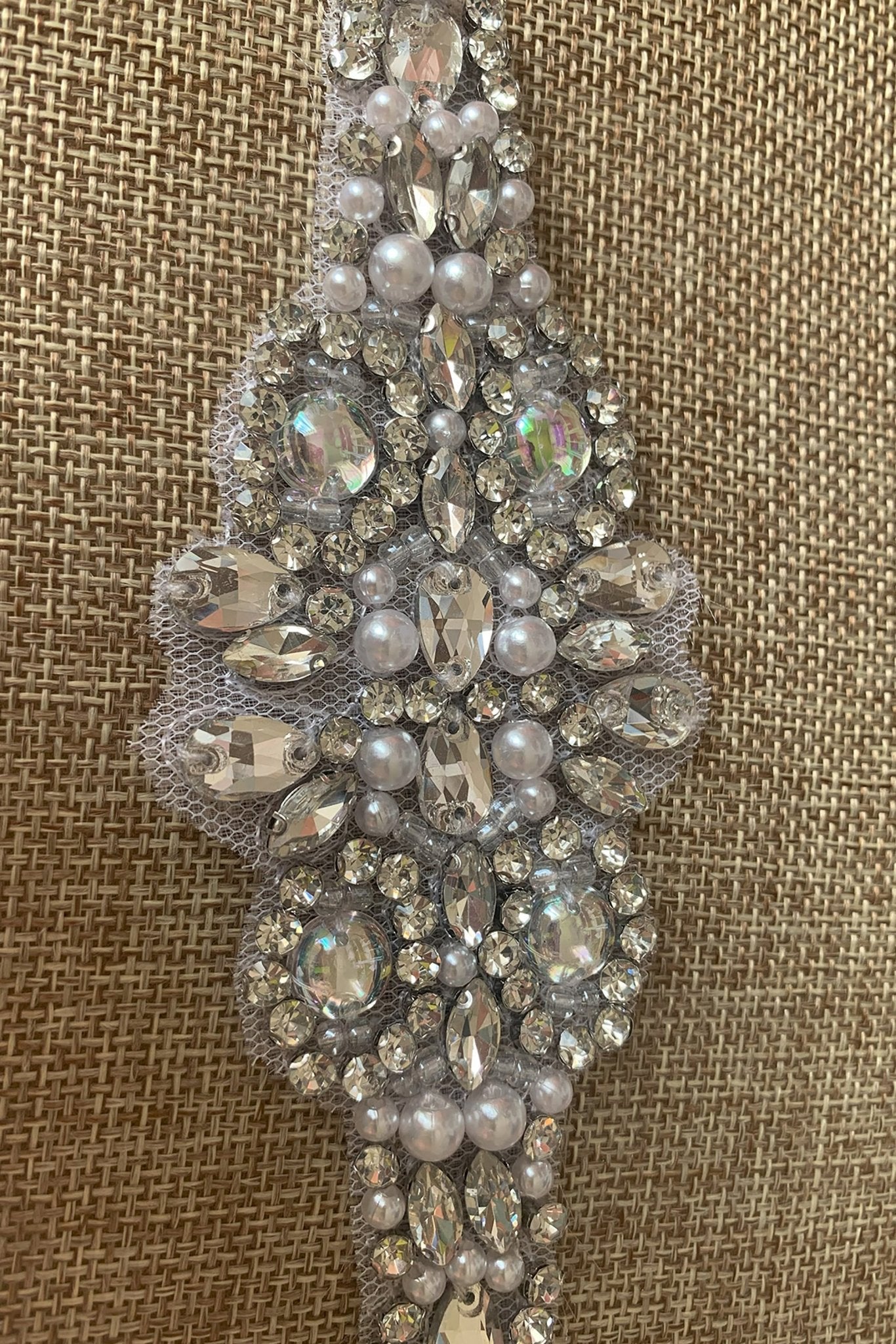 Decorative silver belt with pearls and crystals on a textured brown background
