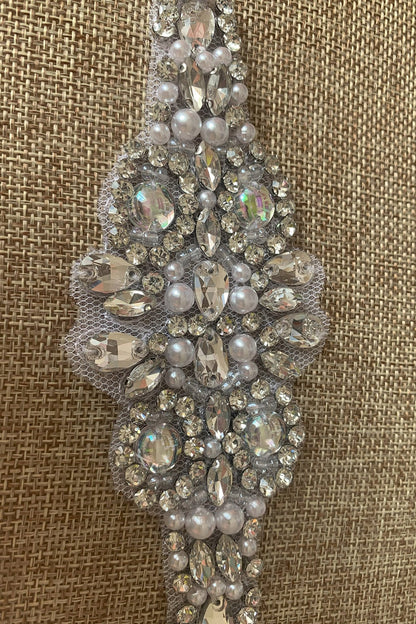 Decorative silver belt with pearls and crystals on a textured brown background
