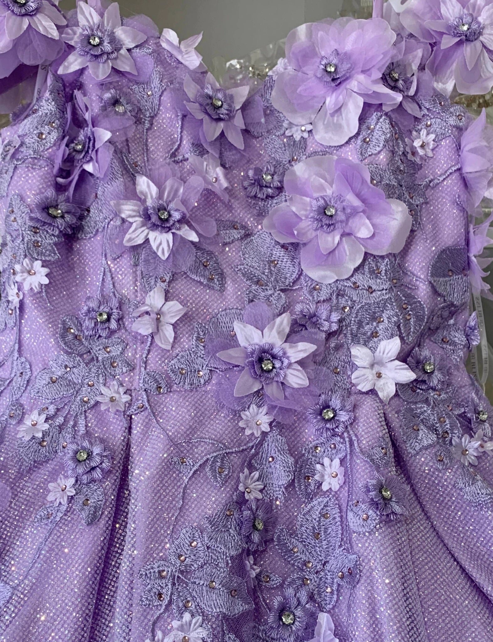 Lilac fabric close-up kids mini quinceañera mini quince dress with floral lace embroidery and bead embellishments.