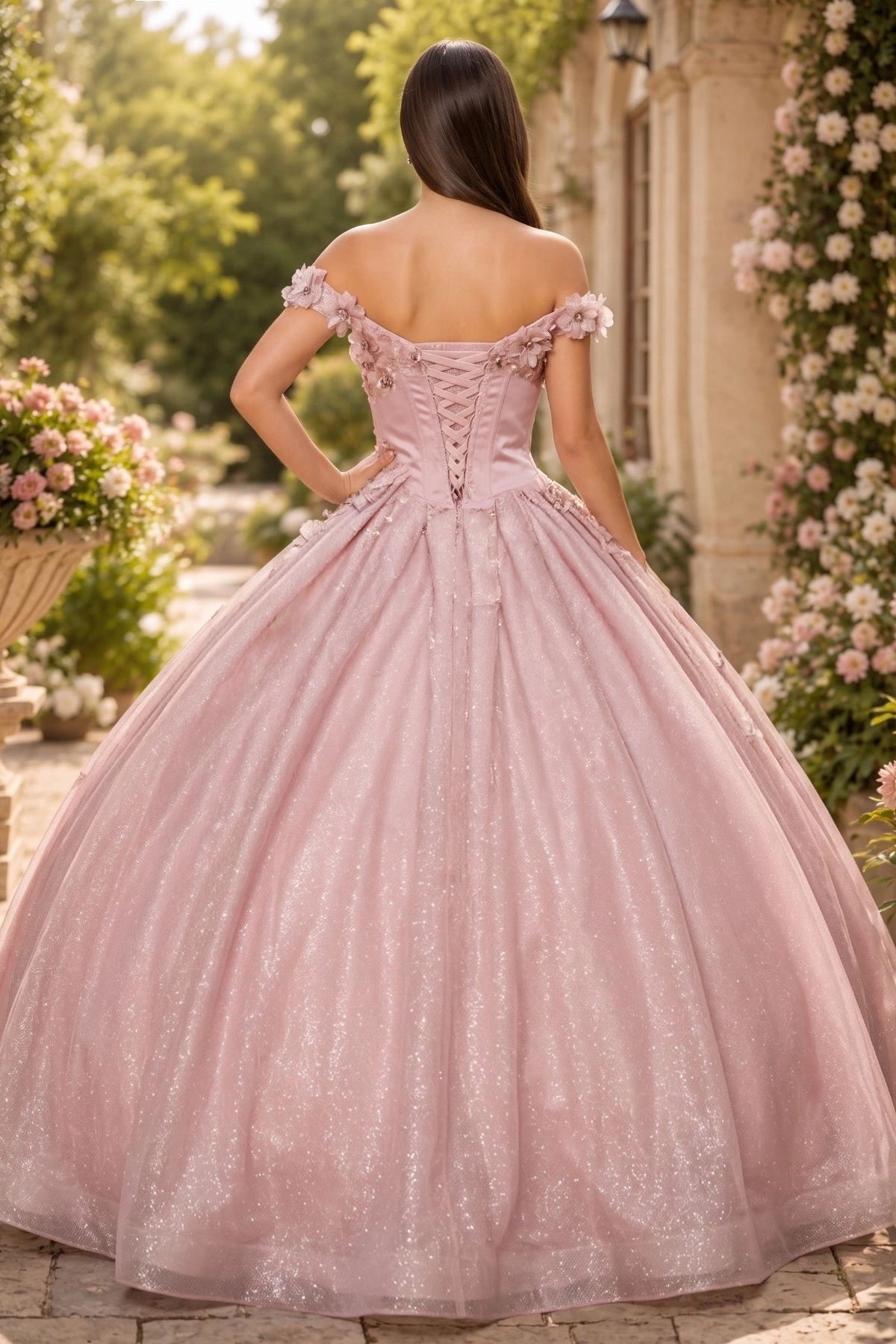 Displayed in a back view, the Dusty Rose quinceañera dress has lace-up back and sweeping glitter skirt.