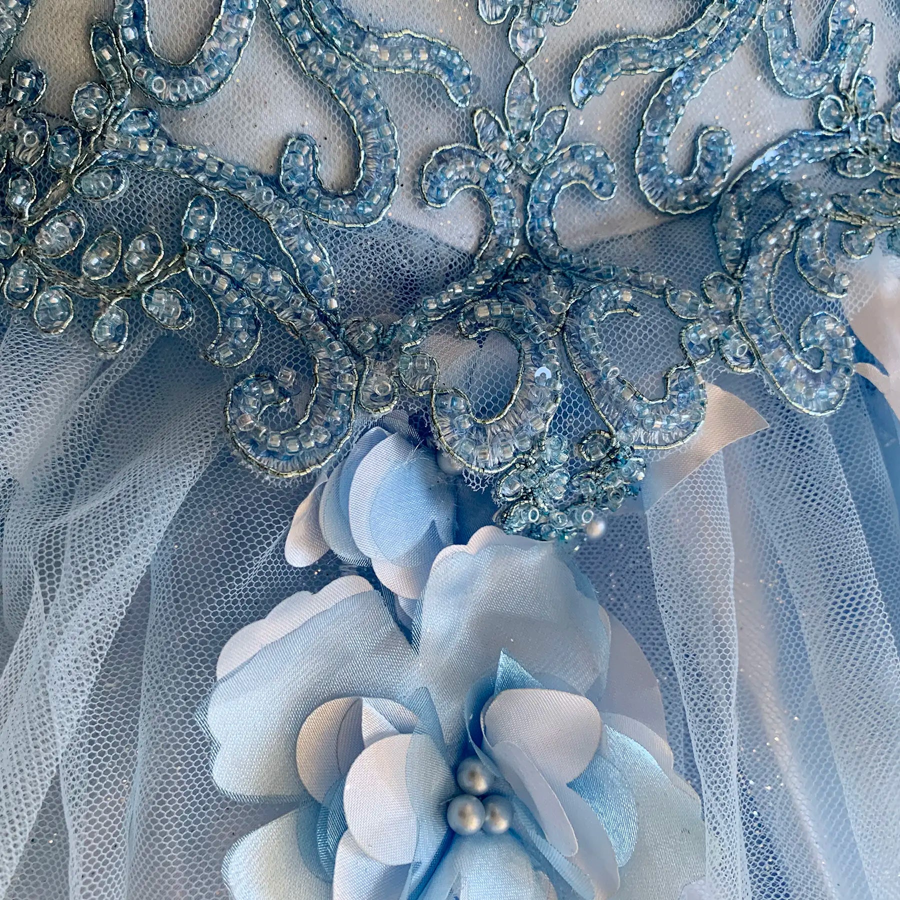 Close-up of blue mini quince dress with floral applique satin-like fabric texture and layered design detail