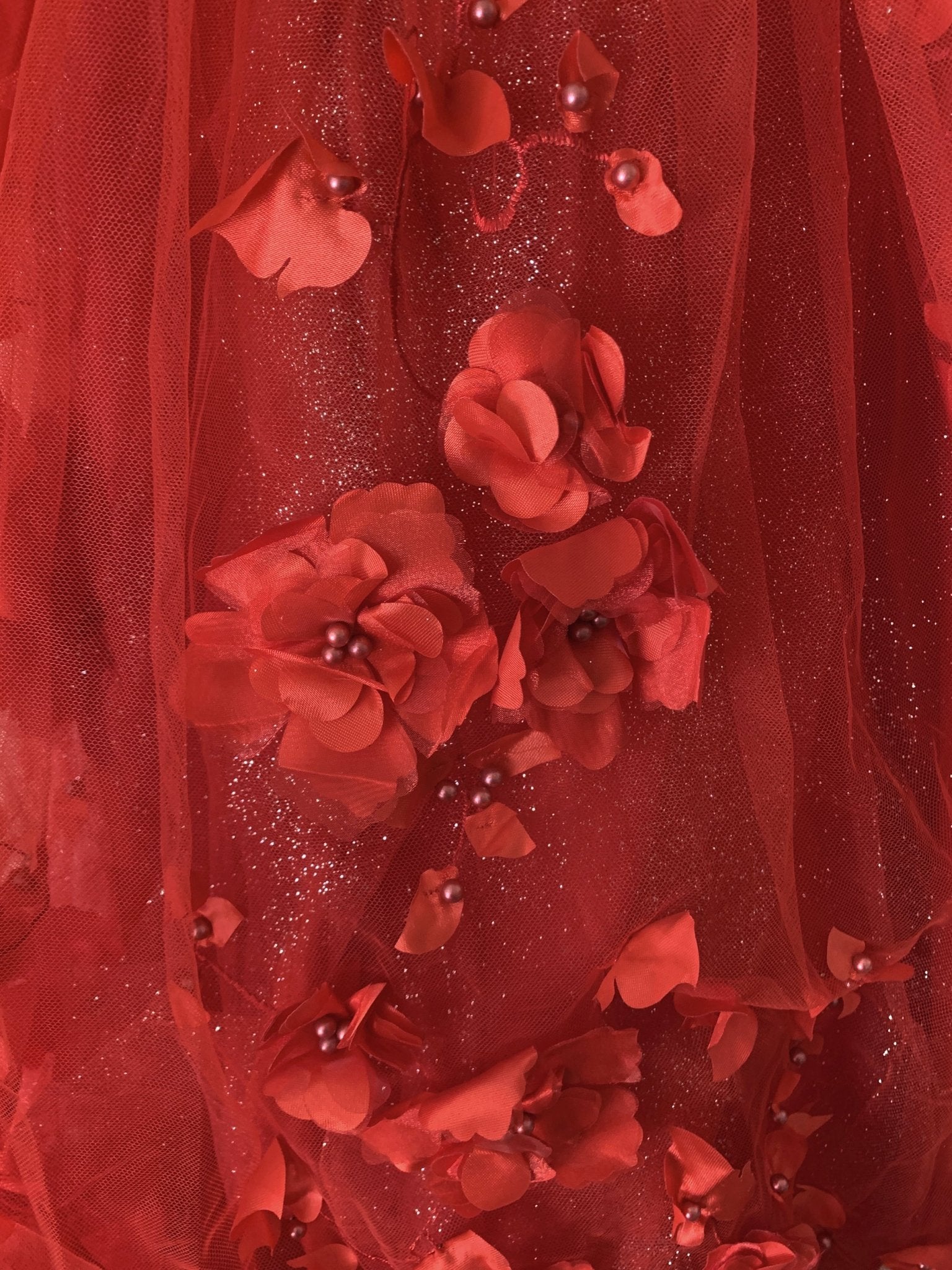 Red detail view kids mini quinceañera mini quince dress showing single 3D floral applique with pearl and stone accents.