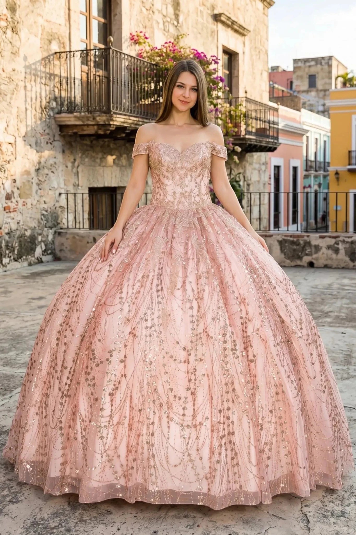 Front view of a woman wearing rose gold quinceanera ball gown with sweetheart neckline, gold embroidery, and glitter bodice